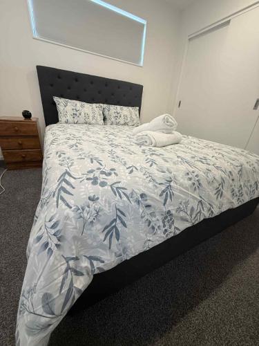 a bedroom with a bed with a blue and white comforter at Reeves awesome stay in Auckland