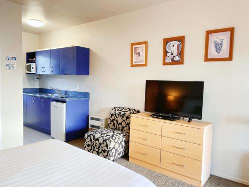 a room with a bed and a tv and a chair at Anchorage Motel Apartments in Te Anau
