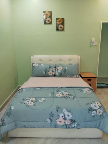 a bed with a blue comforter with flowers on it at Homestay Klang in Klang