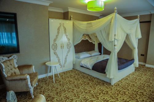 a bedroom with a canopy bed and a chair at My Suit Residence & Hotel in Samsun