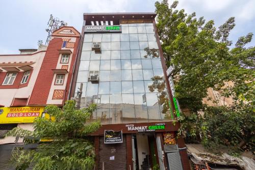 a tall building with a reflection in the windows of it at Hotel Mannat Green Near Naraina Vihar Metro Station in New Delhi