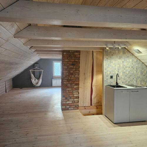 an attic kitchen with a brick wall and wooden ceilings at Leniuszkowo Święty Spokój in Zaleszany