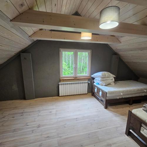 a attic room with two beds and a window at Leniuszkowo Święty Spokój in Zaleszany