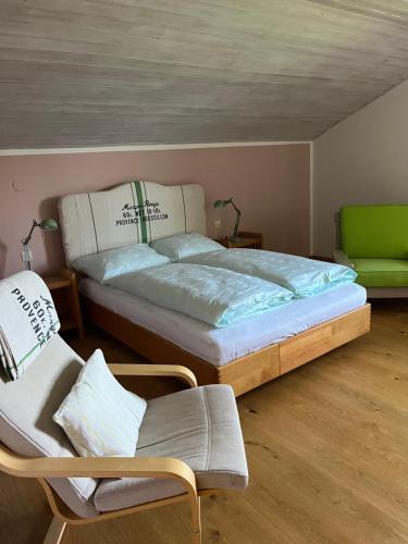 a bedroom with a large bed and a chair at Golf und Berglodge Velden am Wörthersee in Köstenberg
