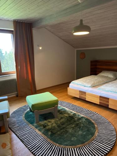 a bedroom with a bed and a green ottoman at Golf und Berglodge Velden am Wörthersee in Köstenberg