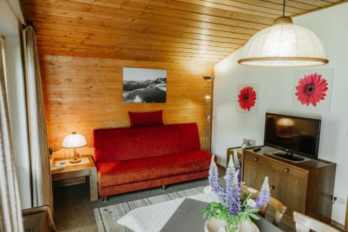 a living room with a red couch and a television at Almblick Appartements in Sankt Jakob in Defereggen