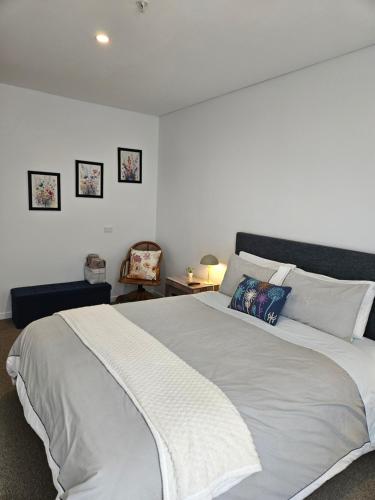 a bedroom with a large white bed and a chair at Modern, Ground floor , CBD, Free parking, 2-3 Beds in Christchurch