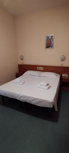 a bedroom with a white bed with two napkins on it at Hotel Acerboli in Rimini