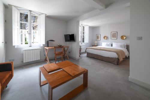 a white bedroom with a bed and a table at la Maison Molière in Arles