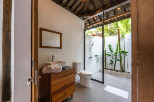 a bathroom with a toilet and a glass door at Terra Clementia in Watukarung