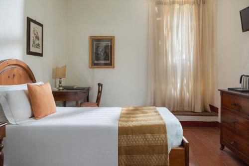 a bedroom with a bed and a desk and a window at Relais Vignale & Spa in Radda in Chianti