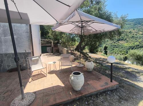 a patio with an umbrella and chairs and a table at L'Antica Quercia B&B in CastellʼUmberto