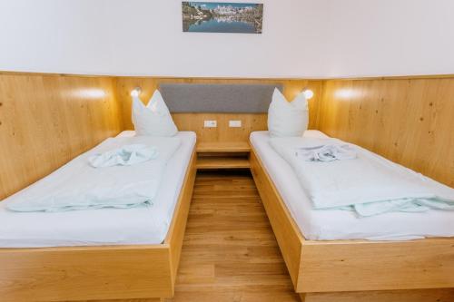 two beds in a small room with wooden walls at Pension Bergbauernhof Irxner in Schladming