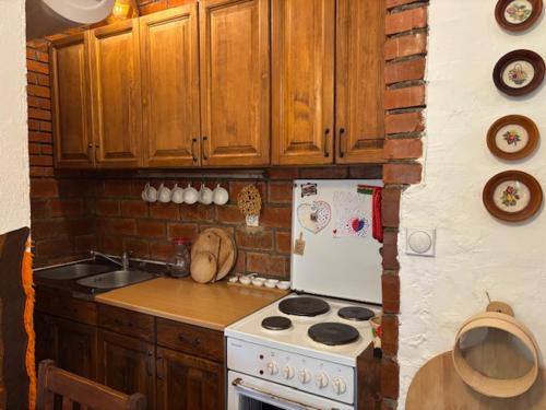 a kitchen with a white stove and wooden cabinets at Етно кућа Нана Добра in Dimitrovgrad