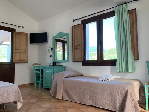 a bedroom with two beds and a table and a mirror at Cort'e Nastasj in Tertenìa