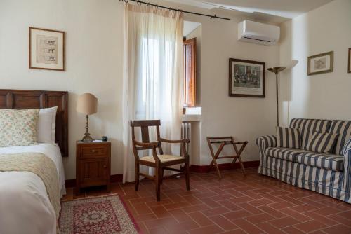 a bedroom with a bed and a chair and a couch at Relais Vignale & Spa in Radda in Chianti