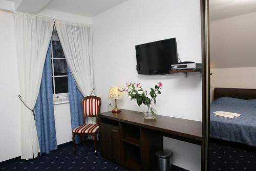a hotel room with a desk and a bed and a television at Birutes Uostas in Šventoji