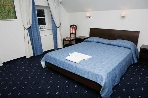 a hotel room with a bed with a blue blanket at Birutes Uostas in Šventoji