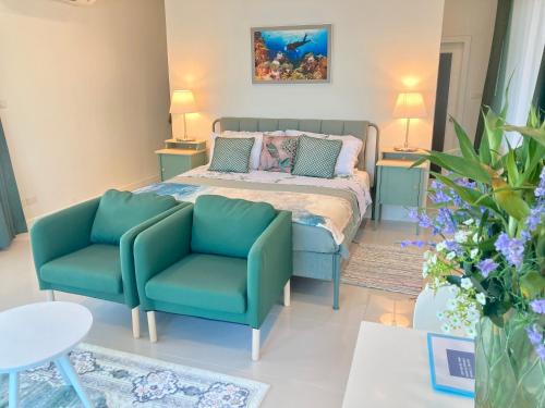 a bedroom with a bed and two blue chairs at Love at First Sight in Chumphon