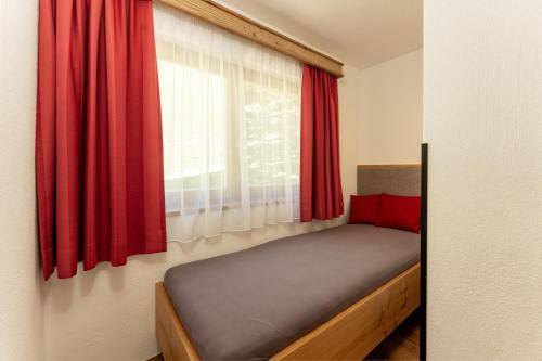 a bed in a room with a window with red curtains at Pension Bergbauernhof Irxner in Schladming