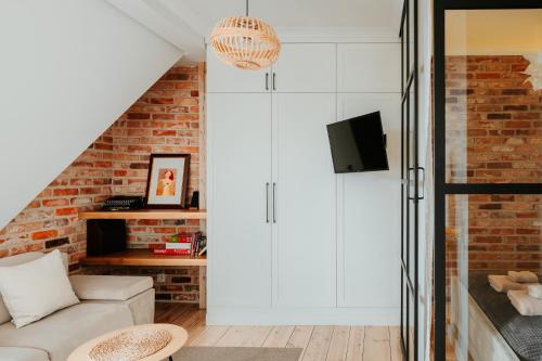 a living room with white cabinets and a brick wall at Klimatyczny Apartament na Bydgoskim Przedmieściu in Toruń