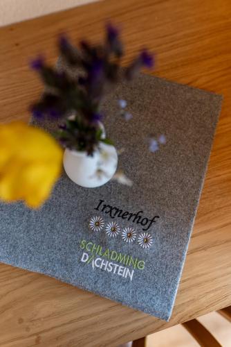 a sign with a vase of flowers on a table at Pension Bergbauernhof Irxner in Schladming