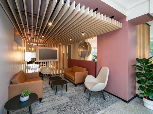 a lobby with a couch and chairs and a tv at B&B HOTEL Berlin-Adlershof in Berlin