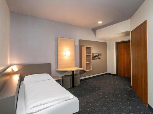 a hospital room with a bed and a desk at B&B HOTEL Berlin-Adlershof in Berlin