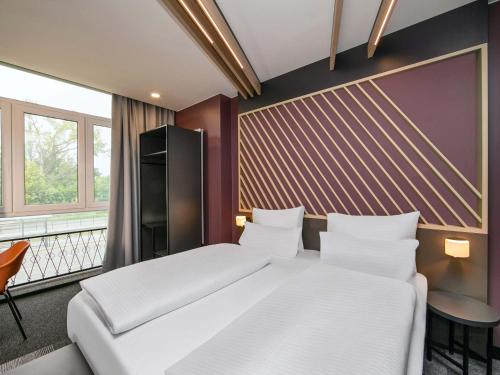 a bedroom with a large white bed and a window at B&B HOTEL Berlin-Adlershof in Berlin