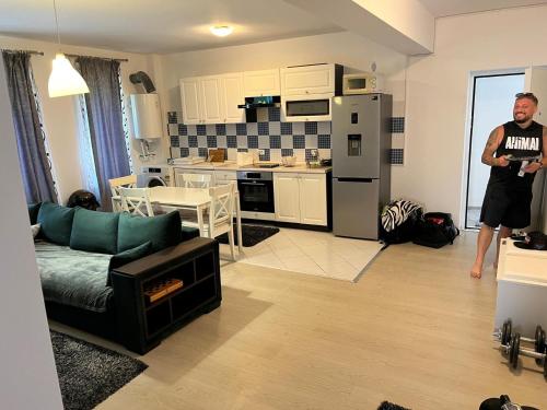 a man standing in a living room with a kitchen at Apartament Mamaia-Nord 5min de mers pe plaja in Mamaia Nord