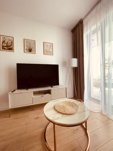 a living room with a table and a large television at Sunrise Euronia in Międzyzdroje
