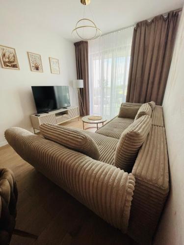 a large couch in a living room with a television at Sunrise Euronia in Międzyzdroje