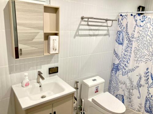 a bathroom with a sink and a toilet and a shower curtain at Love at First Sight in Chumphon