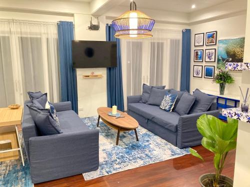 a living room with blue couches and a tv at Love at First Sight in Chumphon