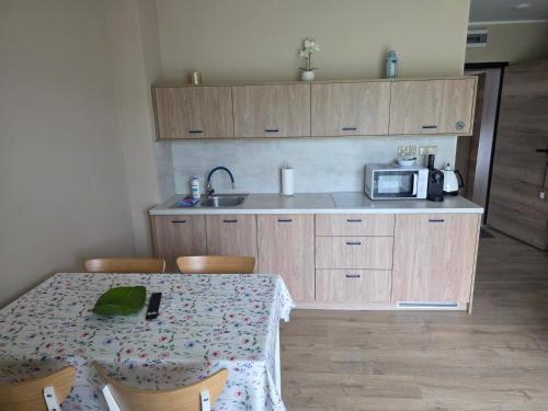 a kitchen with a table with chairs and a microwave at Jagodowy Ski&Spa DeLux apartamenty z widokiem na góry,4km od Zieleniec Ski Arena Podgrzewany basen zewnętrzny latem,bilard,Wi-Fi w cenie Restauracja,balia,sauna na miejscu in Lasowka
