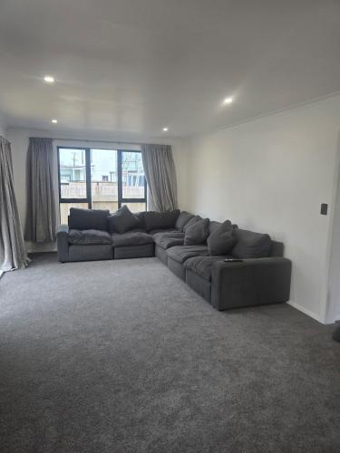 a living room with a couch and a large window at Unwind in Comfort and Style in Upper Hutt