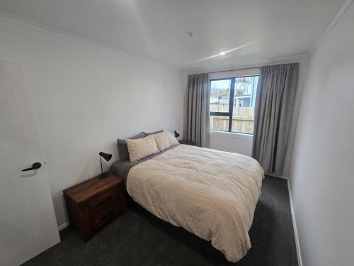 a bedroom with a bed and a window at Unwind in Comfort and Style in Upper Hutt