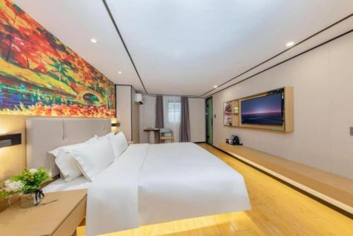 a bedroom with a white bed and a painting on the wall at Yimimi Apartment - Guangzhou 13th Line Yide Road Metro Station in Guangzhou