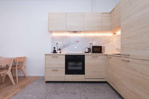 Una cocina con gabinetes de madera y un horno de estufa. en Industrial Stay in Apollo Residence w free parking, en Nivy