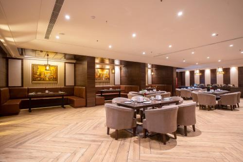 a restaurant with tables and chairs in a room at SANDOZ Pribson Hotel near Golden Temple in Amritsar