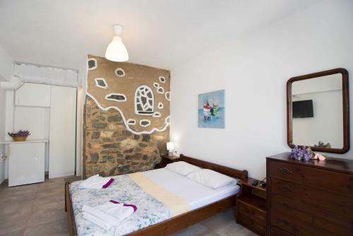 una camera da letto con un letto, uno specchio e una cassettiera di PAROS APARTMENT MELAS b2 a Paroikia