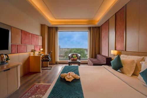 a hotel room with a bed and a large window at SANDOZ Pribson Hotel near Golden Temple in Amritsar
