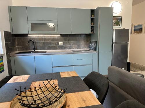 a kitchen with blue cabinets and a table and a couch at Apartments Zlatko & Mira Dorcic in Baška