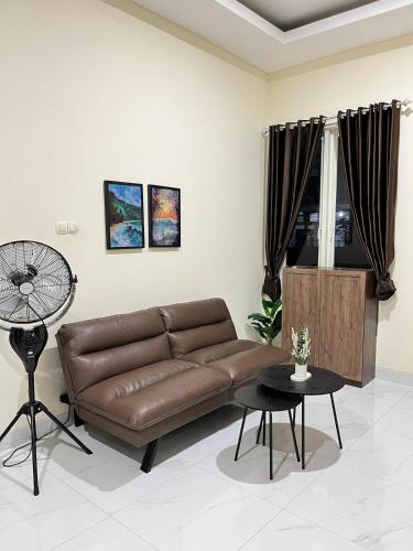 a living room with a brown leather couch and a table at Alya Villa Syariah in Sidoarjo