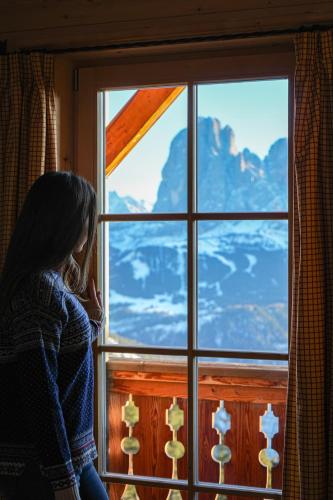 a woman sitting in front of a window looking out at Chalet Resciesa Ortisei in Ortisei