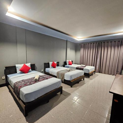 a hotel room with three beds with red pillows at Ridho Malik Hotel in Bumbang