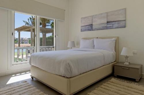 een witte slaapkamer met een bed en een groot raam bij VESTA - Gouna Residence in Hurghada