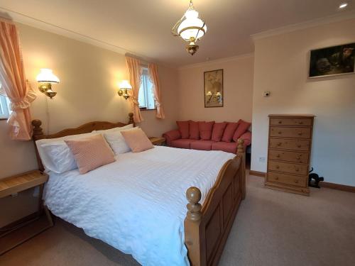 a bedroom with a large bed and a red couch at Duddon Valley Retreat, Lake District National Park, Sleeps 7 in Broughton in Furness