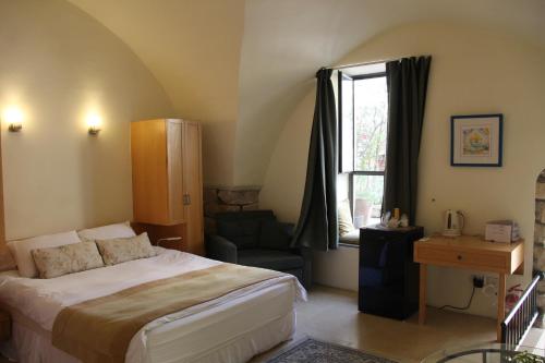 a bedroom with a bed and a chair and a window at Artists' Colony Inn Zefat in Safed