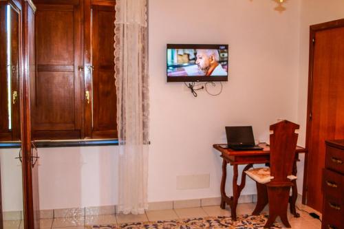 a room with a television on a wall with a desk at La Casetta di Titti in Piano di Sorrento